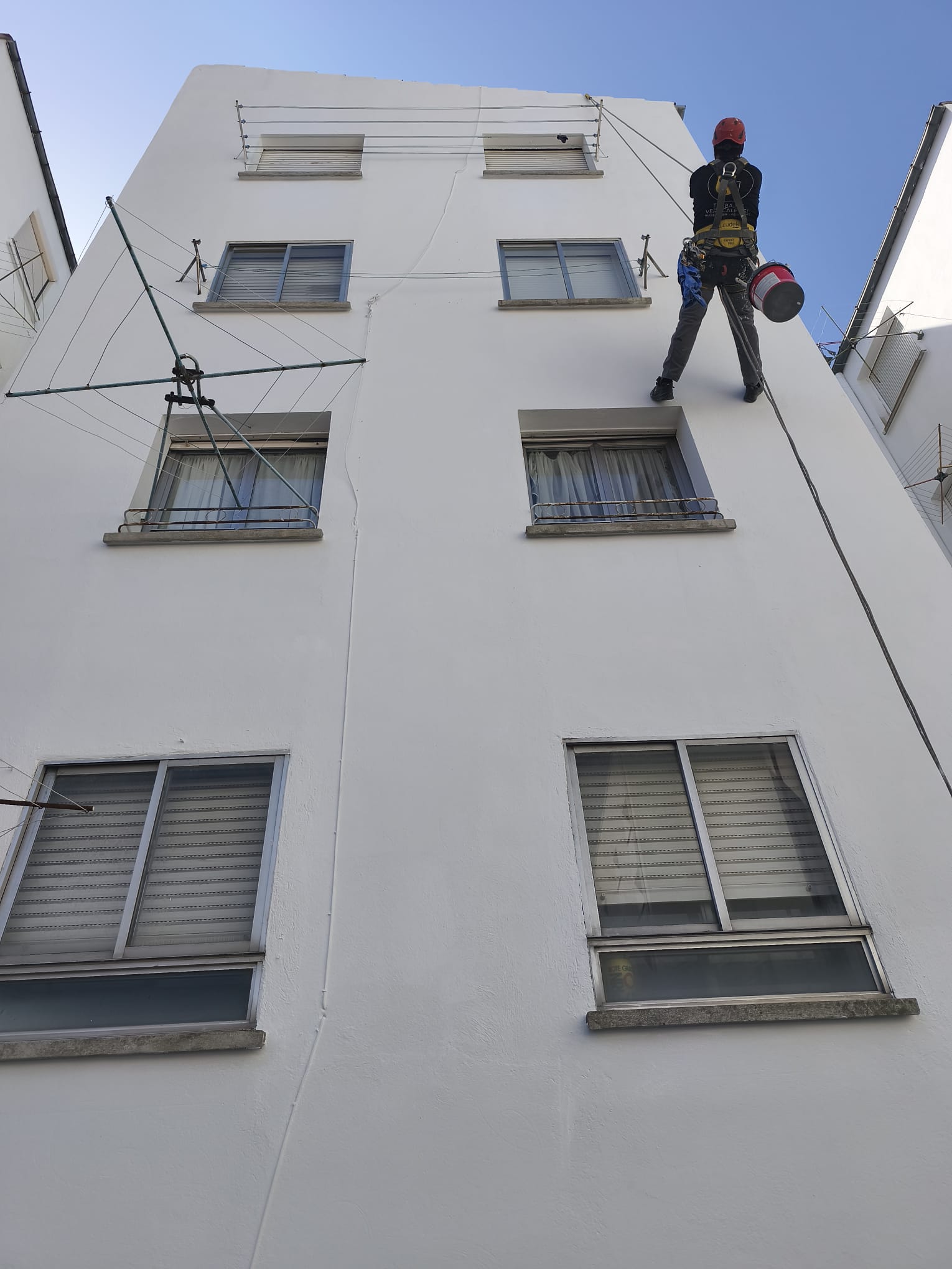 Técnico de AJ Trabajos Verticales pintando una fachada en altura mediante acceso por cuerda